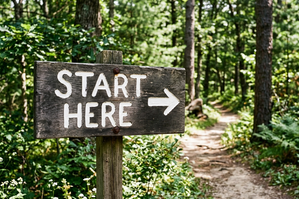 Wooden sign reading 'START HERE' with arrow pointing to a forest path